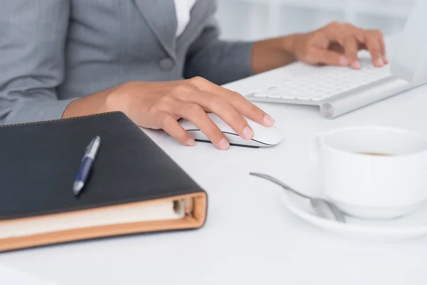 Mão de assistente administrativo utilizando o computador enquanto organiza suas tarefas