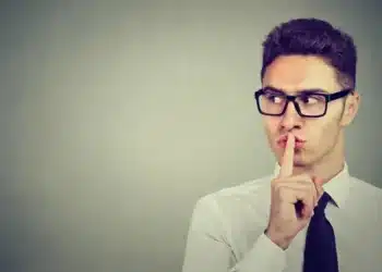 Homem fazendo sinal de silêncio com os dedos, refletindo sobre o impacto do silêncio nas relações.