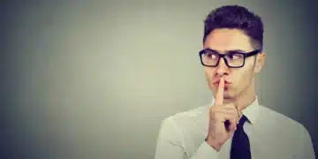 Homem fazendo sinal de silêncio com os dedos, refletindo sobre o impacto do silêncio nas relações.