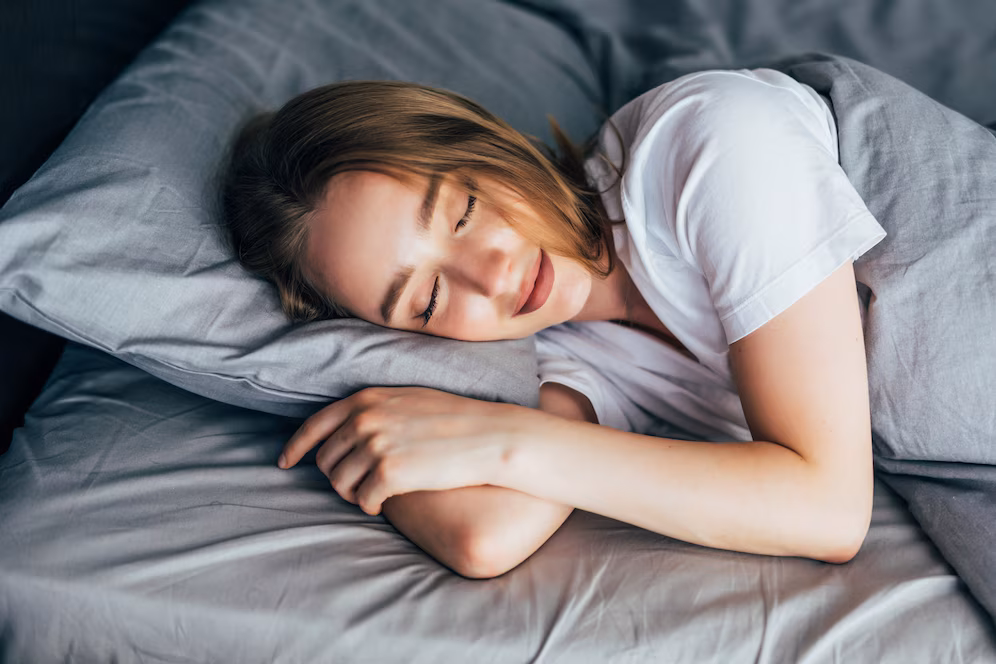 Mulher dormindo tranquilamente em uma cama, simbolizando os benefícios do sono para a saúde do cérebro.