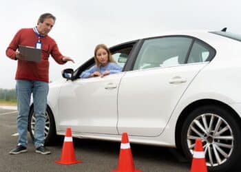 instrutor de autoescola orientando aluna durante aula prática de direção