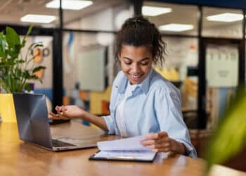 Jovem analisando documentos enquanto usa um laptop, representando cursos técnicos gratuitos
