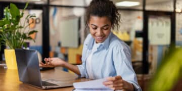 Jovem analisando documentos enquanto usa um laptop, representando cursos técnicos gratuitos
