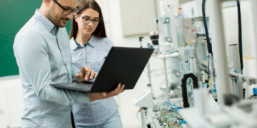 Imagem de dois profissionais em um laboratório, com um deles utilizando um laptop e o outro observando, ilustrando o contexto de cursos técnicos voltados para o mercado de trabalho.