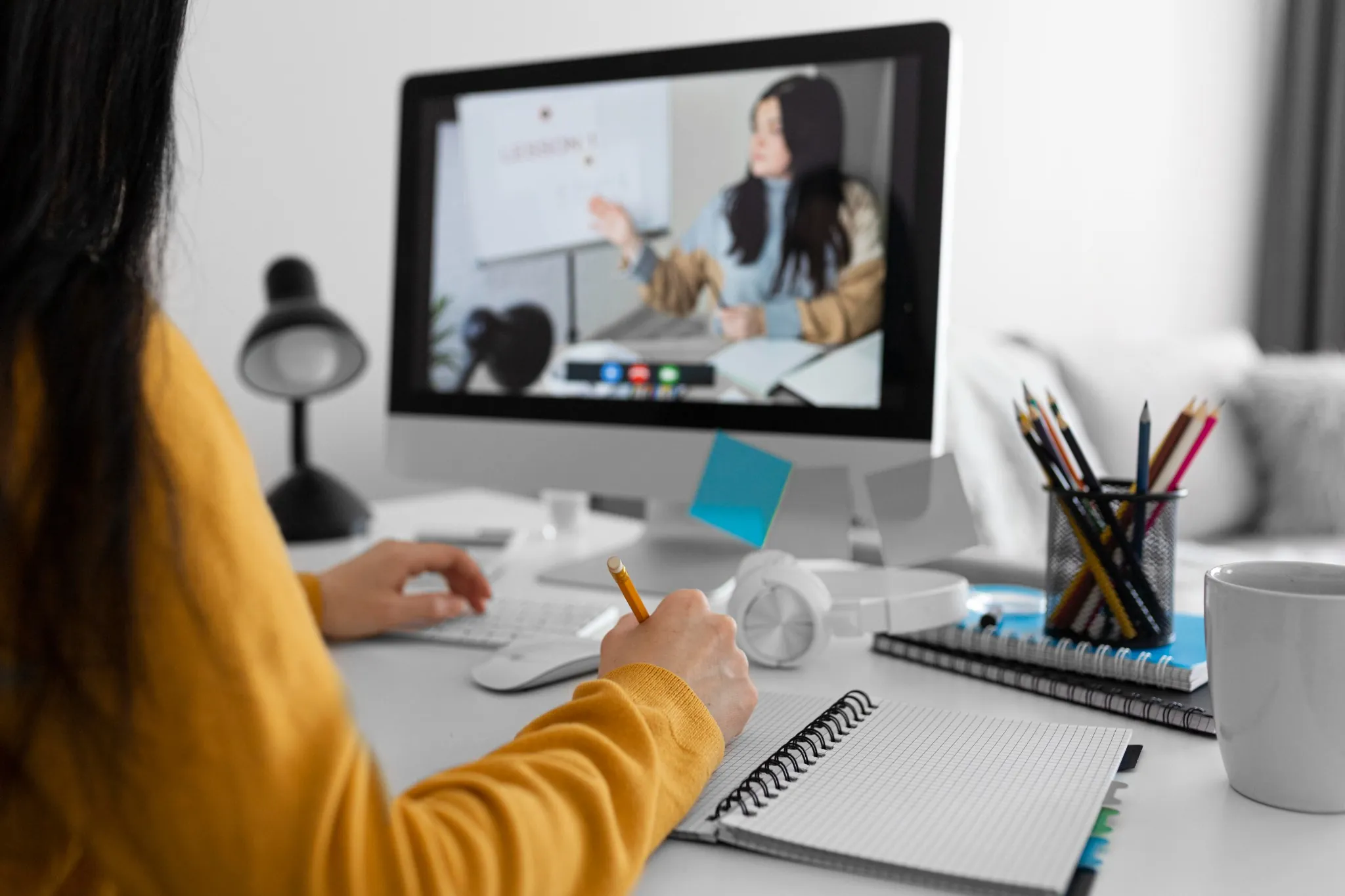 Estudante assistindo aula online de idiomas e fazendo anotações no caderno