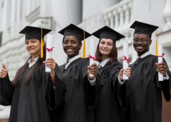 Jovens formandos comemorando com diplomas na mão após conclusão da graduação
