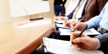 Participantes de um curso técnico em treinamento, concentrados e anotando informações em uma sala de aula.