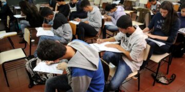 Estudantes participando de um simulado do ENEM, concentrados em suas provas em sala de aula.