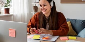 Estudante sorrindo enquanto faz curso técnico online no computador