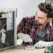 Técnico masculino trabalhando na manutenção interna de um computador aberto usando luvas brancas