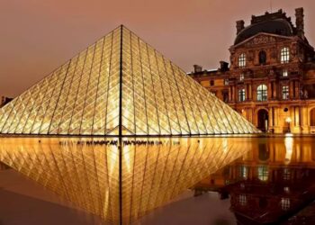 Teste de QI com uma imagem noturna da pirâmide de vidro do Museu do Louvre, refletindo no espelho d'água.