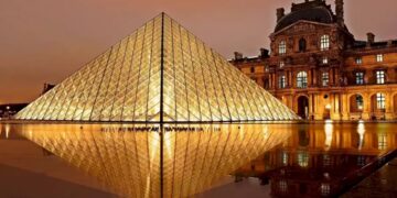 Teste de QI com uma imagem noturna da pirâmide de vidro do Museu do Louvre, refletindo no espelho d'água.