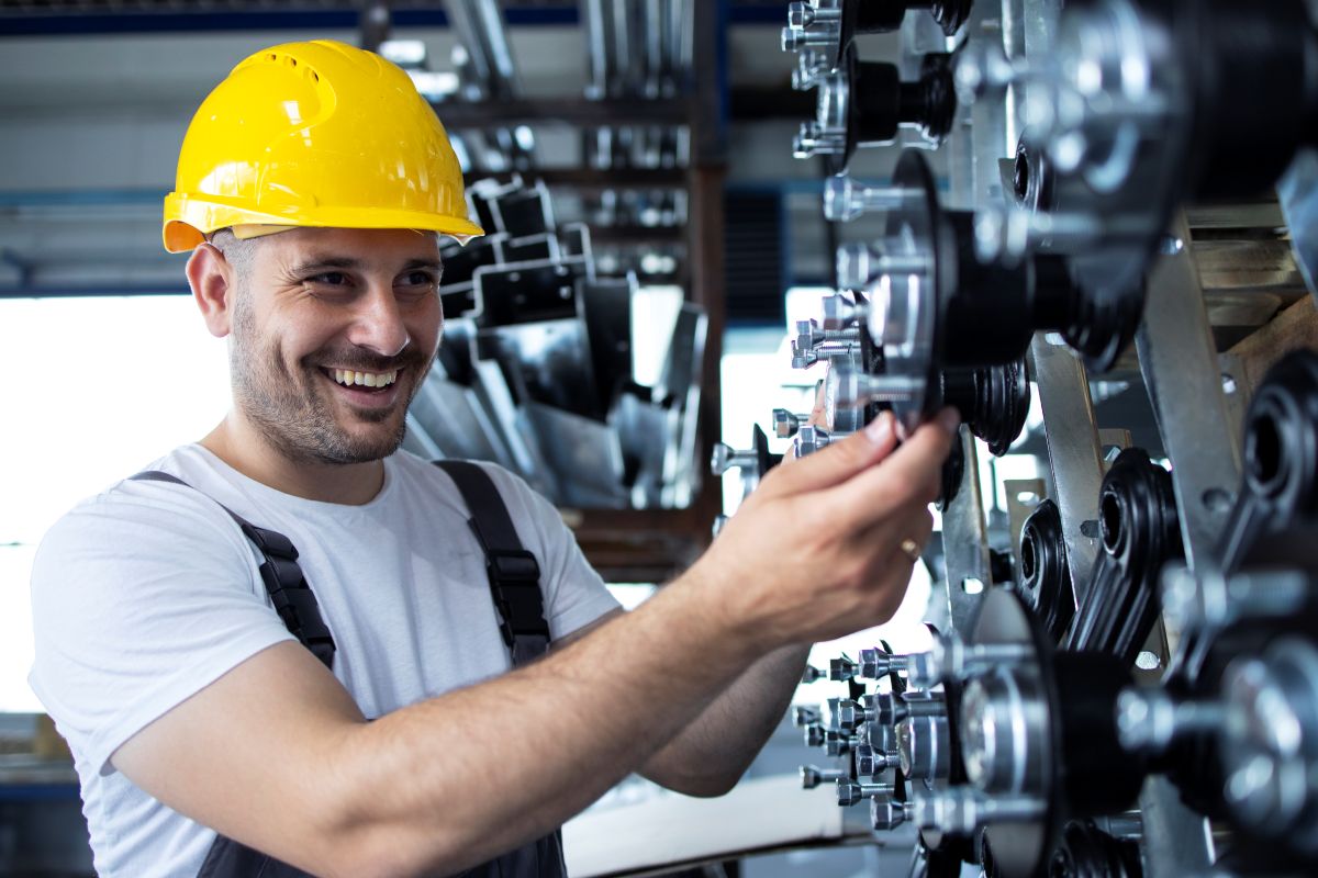 Técnico em mecânica com capacete amarelo trabalhando em máquina industrial