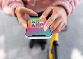 Pessoa segurando um celular com vários ícones de apps de produtividade na tela.