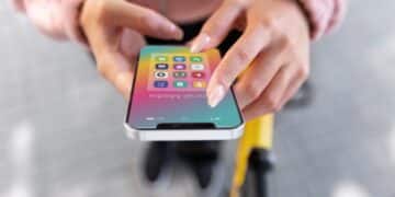 Pessoa segurando um celular com vários ícones de apps de produtividade na tela.