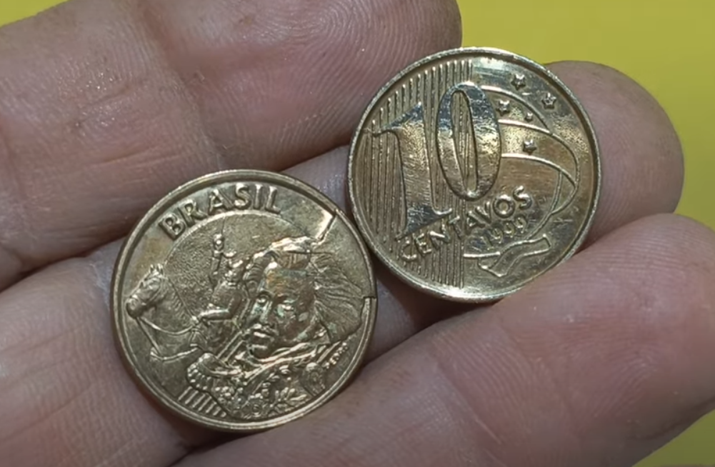 Moeda de 10 centavos de 1999 com possível erro de cunhagem por sobra de metal nas mãos de um colecionador