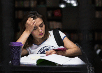 Jovem estudante com expressão cansada revisando conteúdos em ambiente de estudos