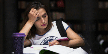 Jovem estudante com expressão cansada revisando conteúdos em ambiente de estudos