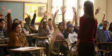 Estudantes levantando as mãos em sala de aula durante uma explicação.
