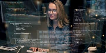 Mulher programando em frente ao computador com códigos flutuantes na tela.