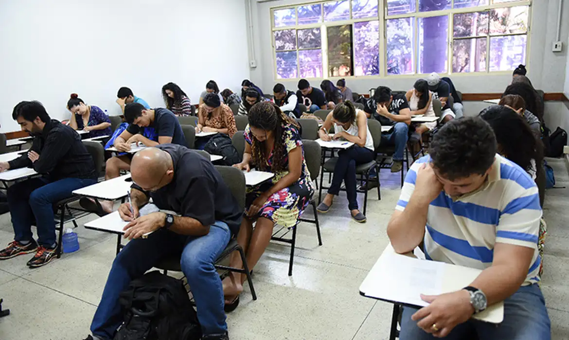 Participantes do Encceja escrevendo durante a prova em sala de aula
