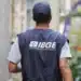 Trabalhador do IBGE usando colete azul, caminhando por uma rua estreita.