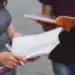 Estudantes interagindo enquanto estudam, com cadernos e canetas em mãos."