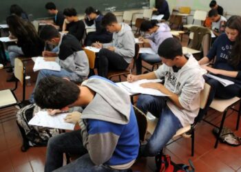 Estudantes concentrados fazendo prova em sala de aula