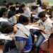 Estudantes concentrados fazendo prova em sala de aula