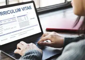 Pessoa preenchendo um currículo em um notebook, representando oportunidades para melhorar a carreira.