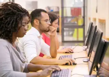 Grupo de estudantes multirraciais treinando em aula de informática