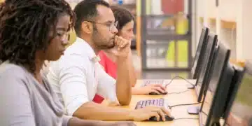 Grupo de estudantes multirraciais treinando em aula de informática