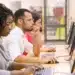 Grupo de estudantes multirraciais treinando em aula de informática