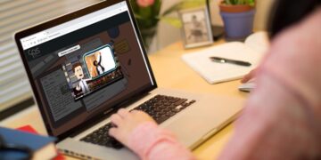 Estudante interagindo com uma plataforma de ensino a distância em um laptop, assistindo a conteúdo educativo digital.