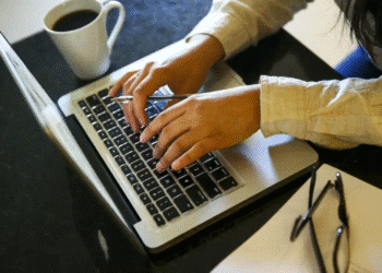 Pessoa digitando no notebook com uma xícara de café ao lado, simbolizando a capacitação e qualificação profissional de jovens na plataforma de cursos gratuitos do governo.