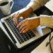 Pessoa digitando no notebook com uma xícara de café ao lado, simbolizando a capacitação e qualificação profissional de jovens na plataforma de cursos gratuitos do governo.