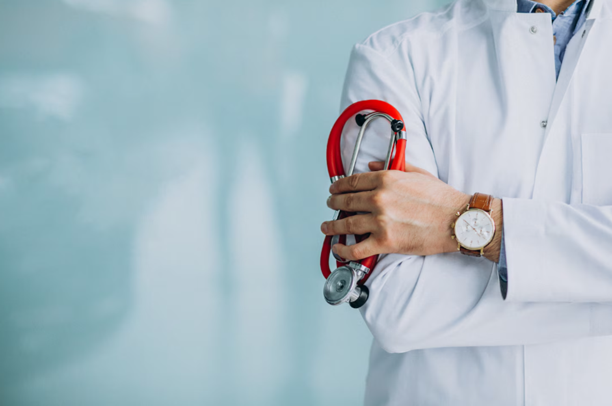 Médico de jaleco branco segurando um estetoscópio, com relógio no pulso.