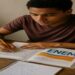 Estudante brasileiro concentrado em mesa de estudos com materiais do ENEM
