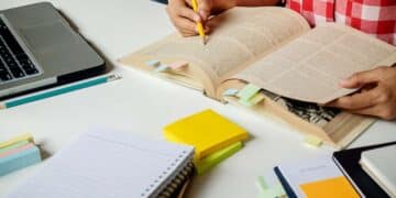 Estudante preparando-se para o Enem, com livros, cadernos e materiais de organização de estudos sobre a mesa.