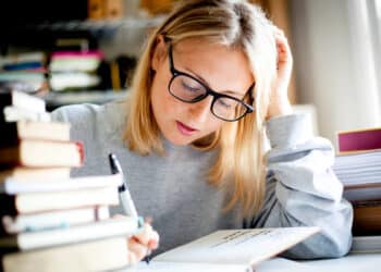 Estudante concentrada revisando um livro, focada em aprender sobre erros de concordância verbal e nominal.
