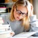 Estudante concentrada revisando um livro, focada em aprender sobre erros de concordância verbal e nominal.