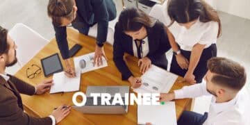 Grupo de profissionais em reunião de negócios, discutindo gráficos e relatórios com foco em programas de trainee