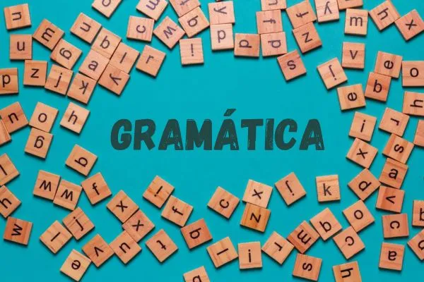 Palavra 'GRAMÁTICA' formada por peças de jogo de letras sobre fundo azul