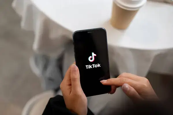 Pessoa utilizando o aplicativo TikTok no celular, representando o regulamento do concurso literário.