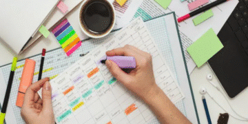 Organização de rotina de estudos para Enem e Vestibulares com planejamentos e materiais escolares sobre a mesa, incluindo canetas, marcadores e uma xícara de café.