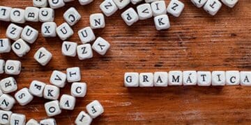 Palavra 'GRAMÁTICA' formada por blocos de letras sobre uma mesa de madeira. Saiba as regras de gramatica.