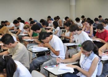 Estudantes realizando prova do vestibular em sala cheia.