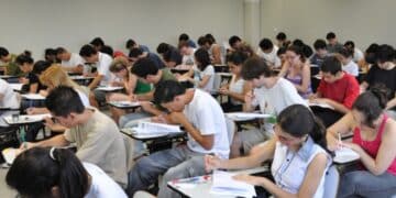 Estudantes realizando prova do vestibular em sala cheia.
