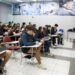 Professor ensinando em uma sala de aula cheia de alunos, simbolizando o processo de aprendizado e a preparação para o ENEM.