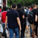Uma multidão de jovens e adultos caminha em grupo, representando os candidatos que se preparam e comparecem às provas do ENEM.